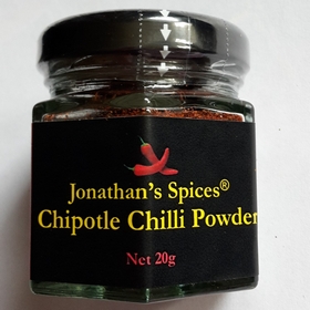 A hexagon shaped glass jar with a yellow, red and black label containing Jonathan's Spices chipotle chilli powder