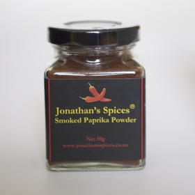 A square shaped glass jar with a black, red and yellow label containing Jonathan's Spices smoked paprika powder